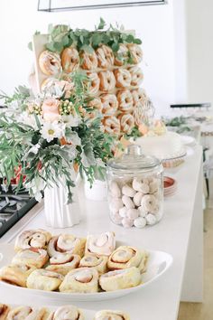 a table topped with lots of pastries next to a vase filled with flowers and greenery