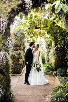 a bride and groom are standing under an archway in the middle of a lush green garden