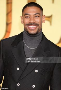 a smiling man in a black suit and turtle neck sweater