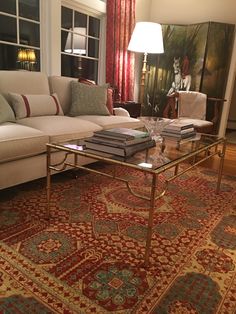 a living room with a couch, coffee table and rug in front of a window