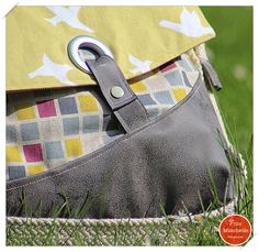 a close up of a purse in the grass with a metal hook on it's side