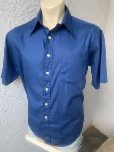 "This deep blue, genuine 1970s vintage, short sleeve, butterfly collared shirt is in excellent vintage condition. SIZE: Pit to Pit: 25\" Collar to hem: 31\" Sleeves: 11\" The tag does not have a size. Check the measurements. I would say it fits like a roomy XL The male mannequin would be 5'10\" 170 lbs. ITEM 125" Blue Cotton Johnny Collar Short Sleeve Shirt, Blue Cotton Short Sleeve Johnny Collar Shirt, Blue Cotton Short Sleeve Shirt With Johnny Collar, Formal Short Sleeve Shirt For Summer, Classic Camp Shirt With Collared Neckline, Blue Cotton Johnny Collar Shirt, Blue Cotton Shirt With Johnny Collar, Classic Blue Short Sleeve Shirt, Fitted Blue Short Sleeve Shirt For Summer