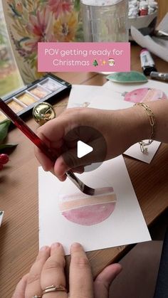 two people are making christmas cards on a table