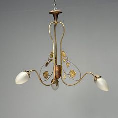 a chandelier with three lights hanging from it's sides and leaves on the bottom