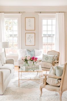 a living room filled with white furniture and lots of window sill space in front of two windows