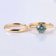 two gold wedding rings with a blue diamond on the top and bottom, sitting next to each other