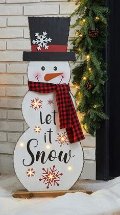 a snowman with a hat and scarf standing in front of a christmas door decoration