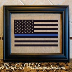 the thin blue line american flag is displayed in a black frame on a countertop