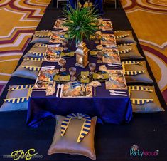 a table set up with plates and place settings for an event or party in blue, gold and white