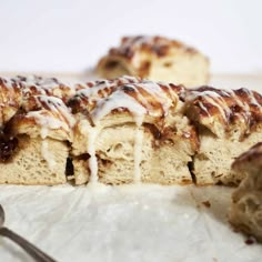 cinnamon roll with icing on top sitting next to a fork