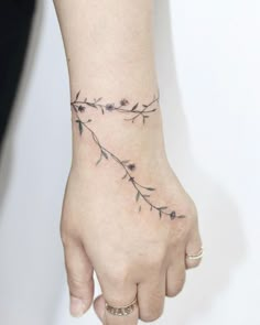 a woman's hand with a flower tattoo on her left wrist and the other arm