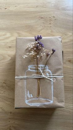 a gift wrapped in brown paper and tied to a string with dried flowers on it