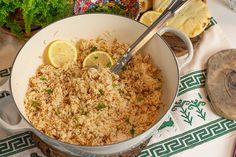 a pot filled with rice and lemon wedges on top of a table next to other foods