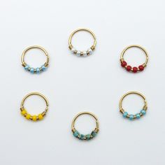 six pairs of gold hoop earrings with beaded beads on each earring, all in different colors