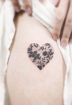 a woman's stomach with a heart shaped tattoo on the back of her thigh