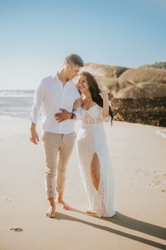 a man and woman are walking on the beach