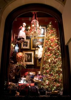 a christmas tree in a window with pictures on the wall and other holiday decorations behind it