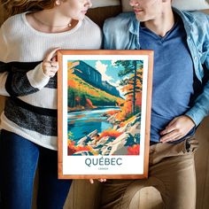 a man and woman holding up a framed poster with the words quebec on it