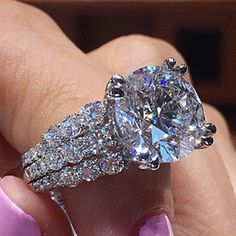 a woman's hand holding an engagement ring with two bands on the band and a large diamond in the middle