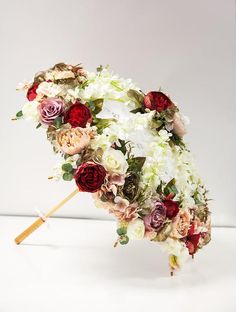 an umbrella made out of flowers on a white background with a wooden stick in the foreground