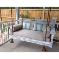 a porch swing with pillows on it