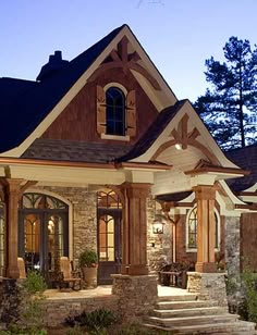 a house with stone and wood trimmings in the front yard at night time