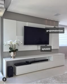 a large flat screen tv mounted to the side of a white wall in a living room