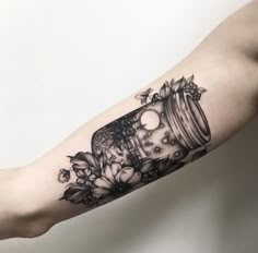 a black and white photo of a jar with flowers on it's arm,