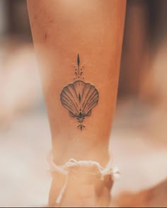 a woman's foot with a shell tattoo on her left leg and an arrow in the middle