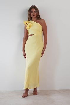 a woman wearing a yellow one shoulder dress with a large flower on the top and bottom