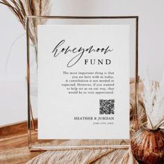 a glass frame with the words engagement fund on it next to some dried plants and a vase