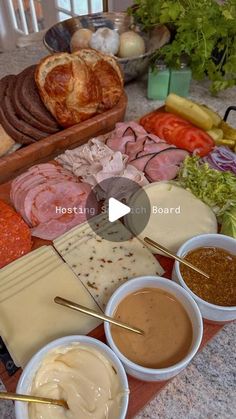 an assortment of meats and cheeses on a cutting board with dipping sauces