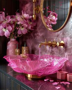 a pink bathroom with flowers and candles on the counter