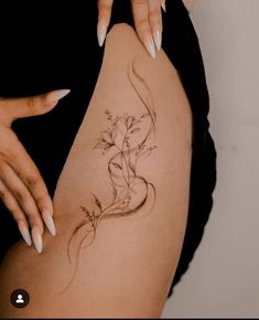 a woman's thigh with flowers on it and her hand touching the side of her leg