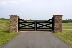 a gated entrance to a grassy field with trees in the background and grass on either side