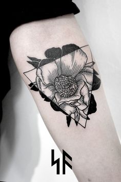 a black and white flower tattoo on the right thigh, with an arrow in the middle