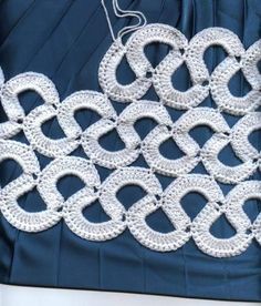 a white crochet doily on a blue cloth with an ironing board in the background