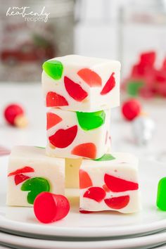 three pieces of white chocolate with red, green and pink candy on top sitting on a plate