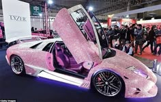 a pink car with its doors open on display