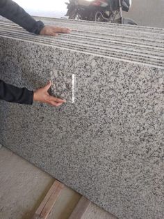 a man standing next to a granite counter top with his hand on the edge of it