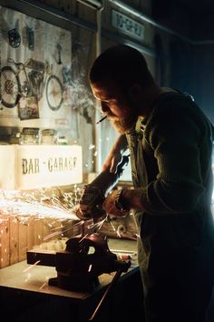 a man working on something in a shop with sparks coming out of his hands,