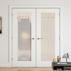 a living room with white walls and two doors that are open to the outside area