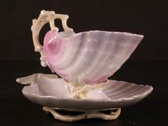 a pink and white shell shaped bowl on top of a saucer