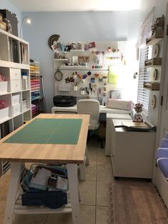 a sewing studio with lots of crafting supplies on the table and shelves in front of it