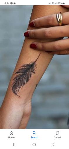 a woman's arm with a feather tattoo on it