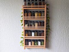 a wooden spice rack with spices and herbs hanging on the wall next to a potted plant