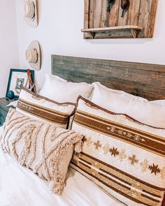 a bed with two pillows and some hats on the head board above it is an antelope