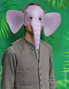 an elephant mask on top of a man's head in front of green leaves