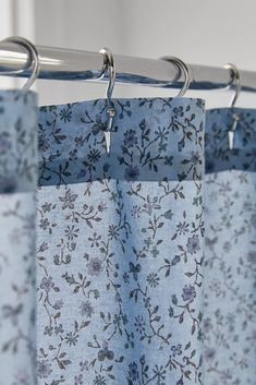 a blue floral curtain hanging from a metal rod