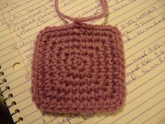 a crocheted bag sitting on top of a notebook